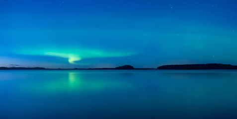 Northern lights dancing over calm lake after the sunset under the blu time