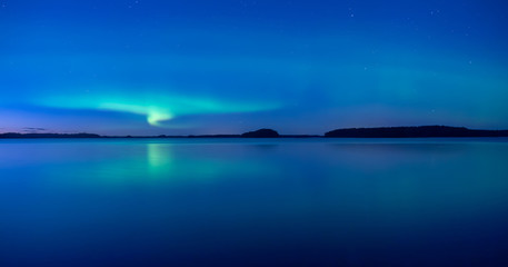 Northern lights dancing over calm lake after the sunset under the blu time