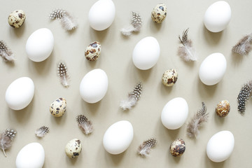 Natural Easter background. Easter egg pattern of white eggs, quail eggs and feathers.