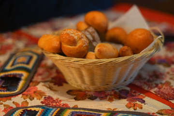 Buns, pastries in a wicker basket on the table, with a tablecloth. Folk style.