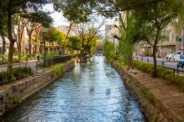 Canal with trees and white lights during daytime in Okayama Japan
