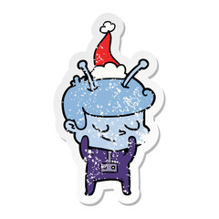 shy distressed sticker cartoon of a spaceman wearing santa hat