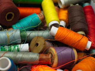 Old multi-colored coils lie in a box. A pile of coils with colored threads. Sewing supplies. Many...