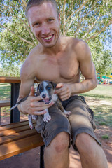 Obraz premium cute puppy on mans legs, while byting him in the finger, broome Australia