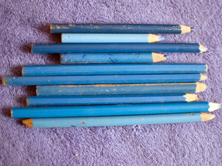 Color pencils on a purple plaid. blue pencils