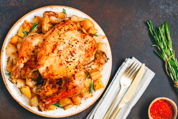 Roasted whole chicken with fried potato on a table.