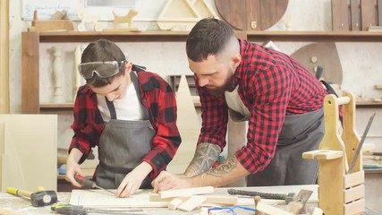 profession, carpentry, woodwork and family concept - carpentery masterclass for little children and their fathers to share basic knowledge of working with wood.