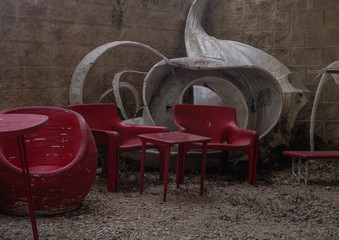 Obraz na płótnie Canvas Outside empty cafe red chairs and table with white modern design, on little stones covered veranda