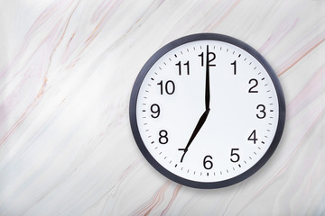 Wall clock show seven o'clock on marble texture. Office clock show 7pm or 7am on marble texture...