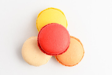 Top view of four sweet French macarons isolated on white, flavours of  lemon, caramel, vanilla and strawberry, pastel colors