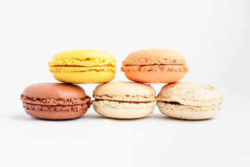 Five sweet French macarons isolated on white, flavours of lemon, caramel, vanilla, coconut and chocolate,  pastel colors