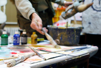 Shallow depth of field on brushes and man painting in the background