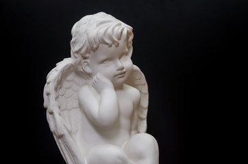 Beautiful white angel on black background close-up. Symbol of love, faith and hope. Place for text