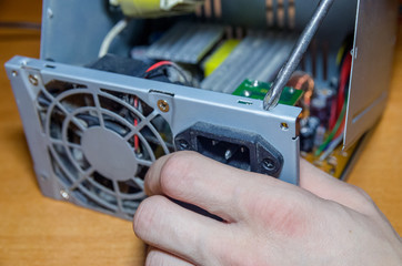 Screwdriver unscrews the computer power supply