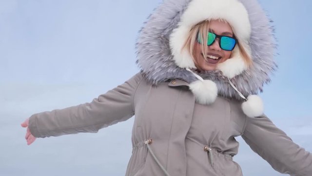 Beautiful girl winter outdoor wearing a fur coat and sunglasses. It is snowing. She is happy in winter. Smiling.