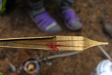 The man is holding a bloody Jew's harp close-up. Playing a musical instrument during a hike. Life in the forest.