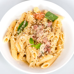 Very simple traditional Italian pasta - penne with pancetta and cheese in a plate on a light background