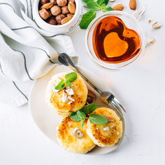 Breakfast or lunch concept. Cottage cheese pancakes with honey, nuts and mint on white background. Top view