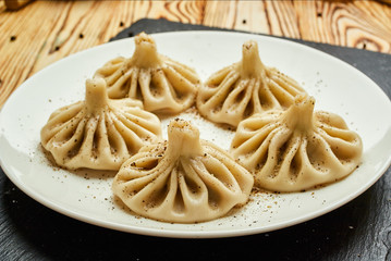 Georgian dumplings Khinkali with meat, greens and tomato spicy sauce Satsebeli on white plate