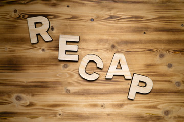 RECAP word made of wooden block letters on wooden board, top view.