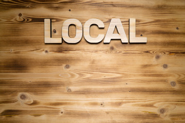 LOCAL word made of wooden block letters on wooden board, top view.