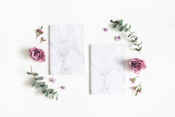 Flowers composition. Paper blank, eucalyptus branches and rose flowers on white background. Wedding invitation card. Flat lay, top view, copy space