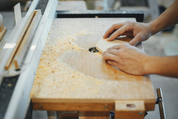 A man carves a tree. The carpenter works in a studio. An engineer provides a tree shape