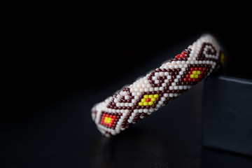 Beige bracelet with oriental pattern on a dark background close up