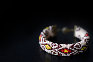 Beige bracelet with oriental pattern on a dark background close up