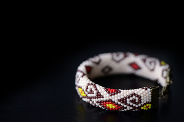 Beige bracelet with oriental pattern on a dark background close up