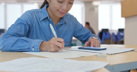 Woman write on the paper with cellphone at home