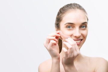 Portrait of smiling woman without make up glues pink patches under her eyes