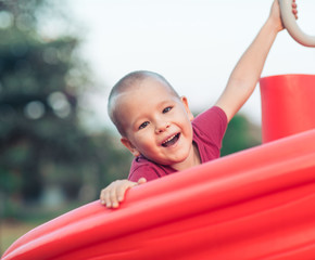 Fototapeta na wymiar Little smiling boy on a slide