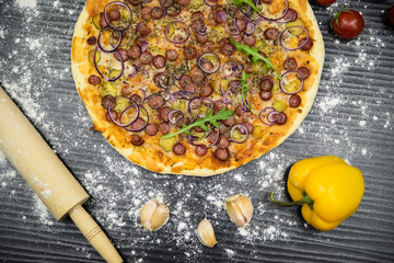 pizza with sausages and pickles on black background