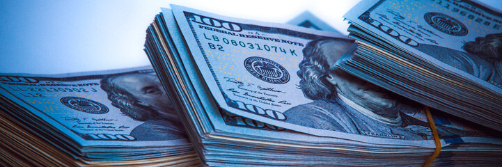 Banknotes of dollars in packs. Dark blue light. - obrazy, fototapety, plakaty