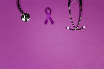Fototapeta premium Purple epilepsy awareness ribbon with stethoscope and copy space on a purple background.