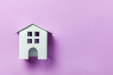Simply design with miniature white toy house isolated on purple violet pastel colorful trendy background. Mortgage property insurance dream home concept. Flat lay top view copy space