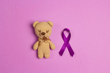 Children's toy with a Purple epilepsy awareness ribbon on a purple background. World epilepsy day.