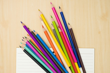 Obraz premium colorful pencils and notebook on wooden background top view. art equipment.