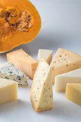 Various types of cheese and pumpkin on white