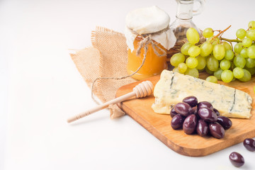 White cheese plate with olives, honey, grapes. Assortment of wine snack, appetizer or gourmet dinner.