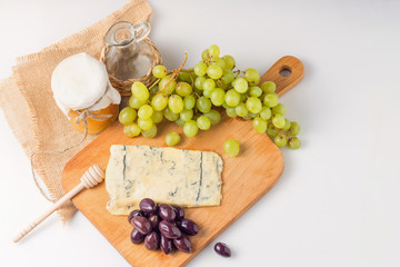 White cheese plate with olives, honey, grapes. Assortment of wine snack, appetizer or gourmet dinner. Top view