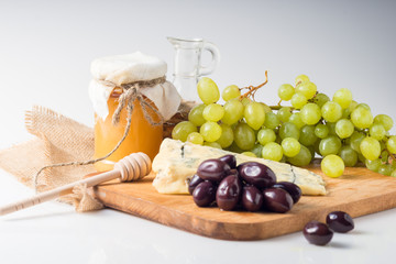 White cheese plate with olives, honey, grapes. Assortment of wine snack, appetizer or gourmet...