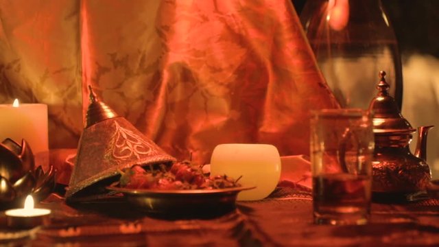 Romantic scene candle lit of a Moroccan theme foreground with soft-focus sliding to reveal the back of a lady getting undress in the background