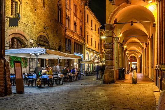 Fototapeta Old narrow street with arcade in Bologna, Emilia Romagna, Italy. Night cityscape of Bologna.