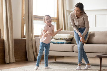 Happy playful cute child daughter laughing dancing with young mom