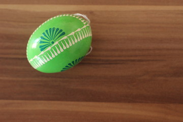 Handbemaltes gr&uuml;nes Osterei isoliert auf Holzhintergrund mit Freifl&auml;che zum Beschriften