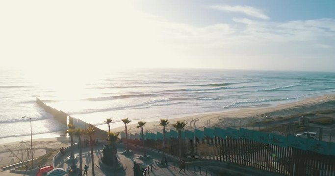 Aerial shot of the wall at the Tijuana - San Diego border in the beach at sunset.