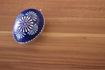 Handbemaltes blaues Osterei isoliert auf Holzhintergrund mit Freifläche zum Beschriften