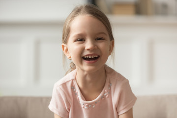 Funny adorable little girl laughing looking at camera, headshot portrait